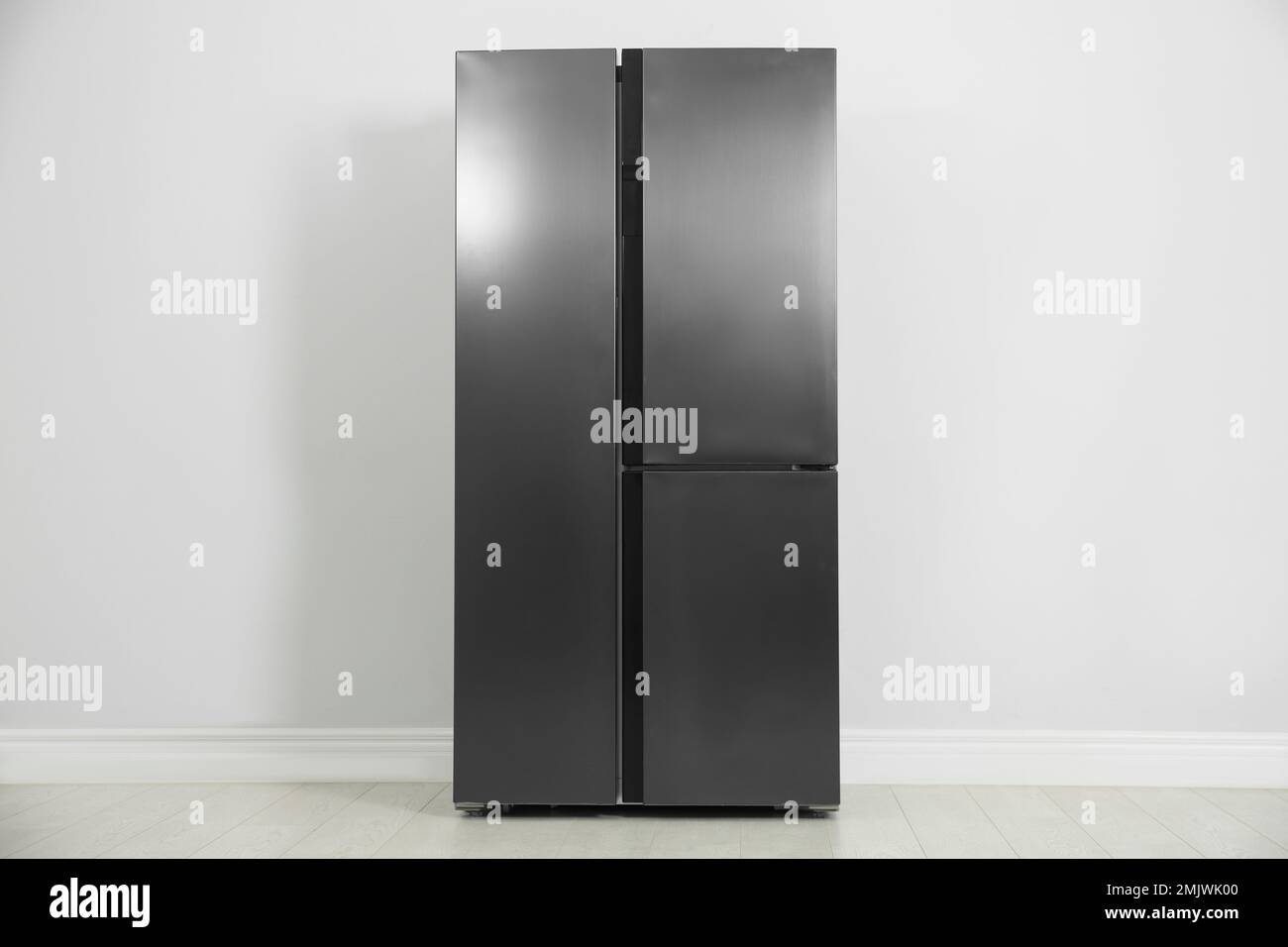 Modern refrigerator near light grey wall. Home appliance Stock Photo