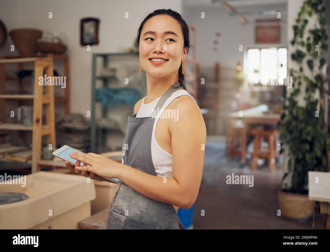 Tablet, small business and woman in pottery workshop for ceramic startup, research and online website. Creative art, ecommerce and asian lady with Stock Photo