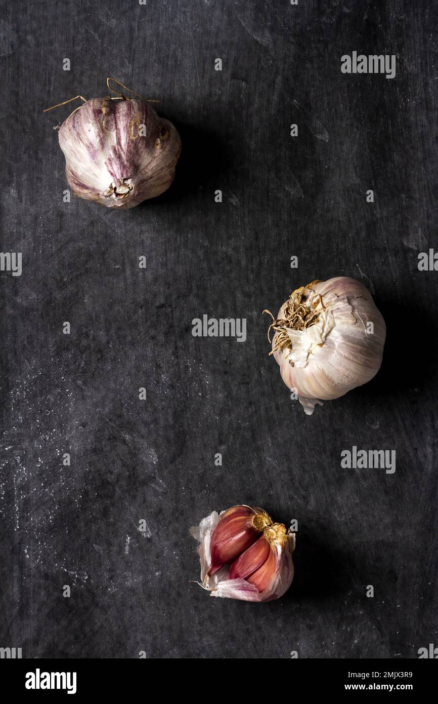 Fresh garlic bulbs and cloves grouped on black background. Flat lay ...