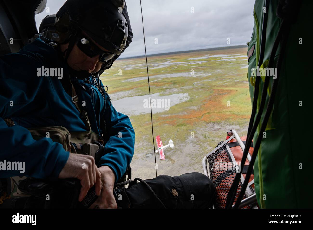 Alaska Air National Guard Capt. Robery Brodsky, a combat rescue officer assigned to the 210th Rescue Squadron, prepares to conduct a rescue mission in a HH-60G Pave Hawk at Point MacKenzie, Alaska, Sept. 1, 2022. After a Christen A-1 Husky crashed into a marsh, National Guardsmen rappelled and conducted a rescue operation, ensuring the aircraft was safely vacated. Stock Photo