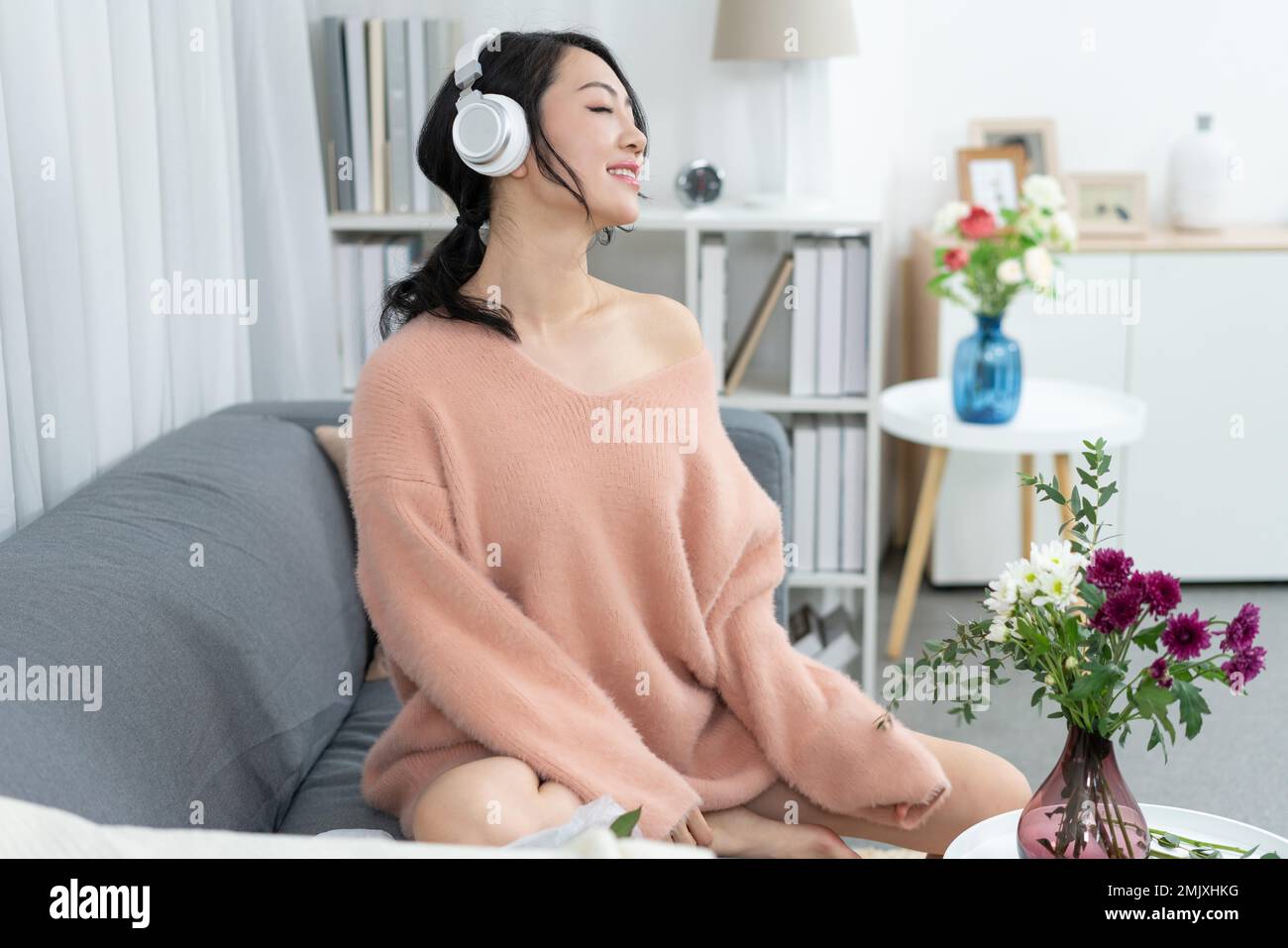 Young woman sitting on the sofa listening to music Stock Photo - Alamy
