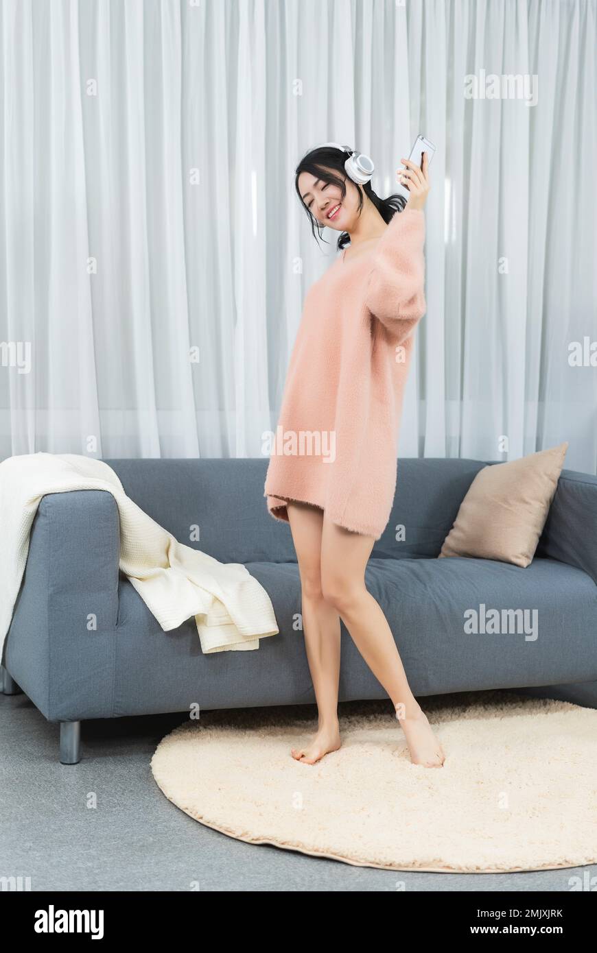 Young woman sitting on the sofa listening to music Stock Photo - Alamy