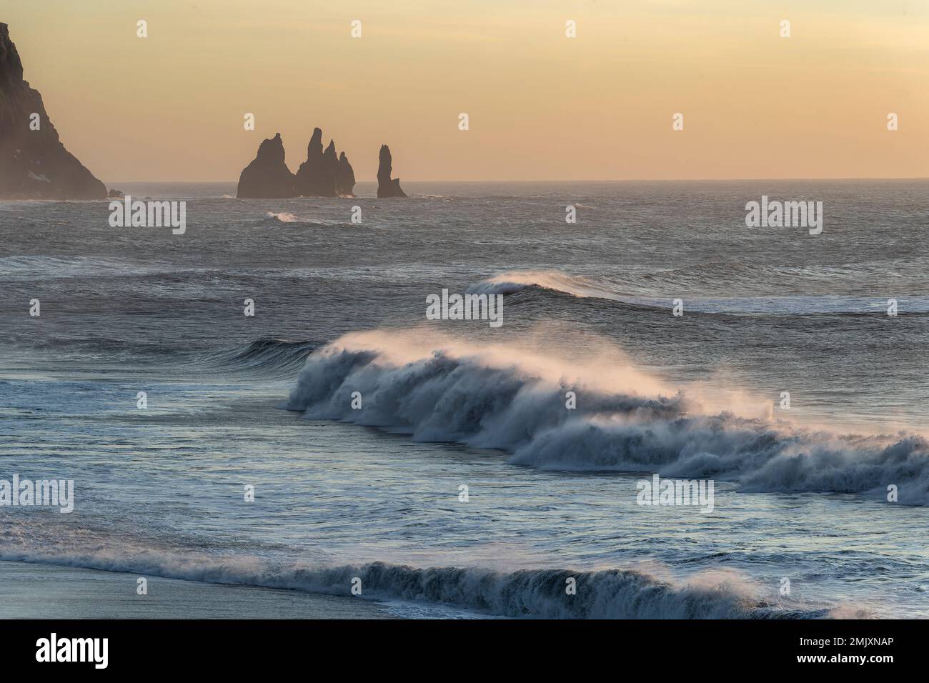 Sunset in Iceland with rolling waves and rock stacks Stock Photo