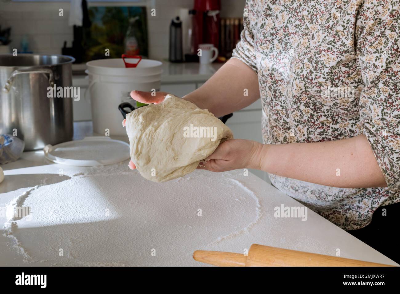 Woman mixing yeast dough for making homemade donuts on white countertop Stock Photo