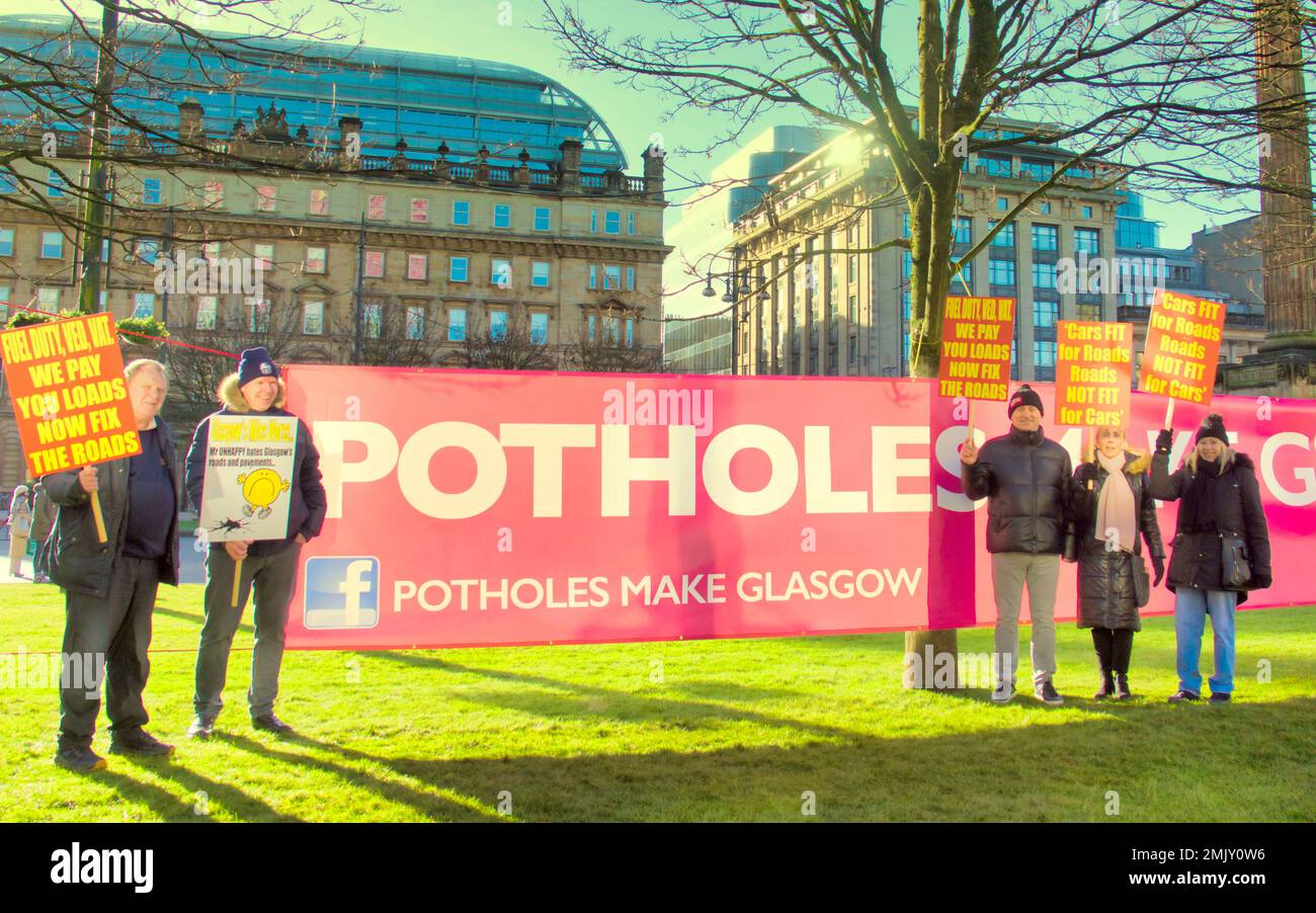 Glasgow, Scotland, UK 28th  January, 2023. Pothole protest outside council headquarters in george square saw a large crowd of placard waving demonstrators with a crowd funded banner gain the approval of passing motorists as they posed by the side of the road with a a large pothole. Credit  Gerard Ferry/Alamy Live News Stock Photo