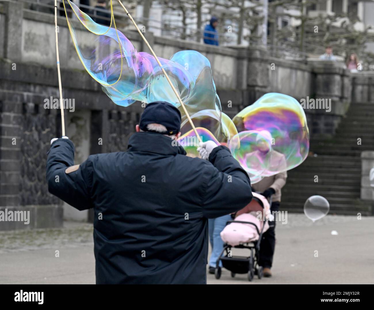 Duesseldorf, Germany. 28th Jan, 2023. A man produces giant soap bubbles on the banks of the Rhine to the delight of walkers in dreary weather with temperatures around two degrees. Credit: Roberto Pfeil/dpa/Alamy Live News Stock Photo