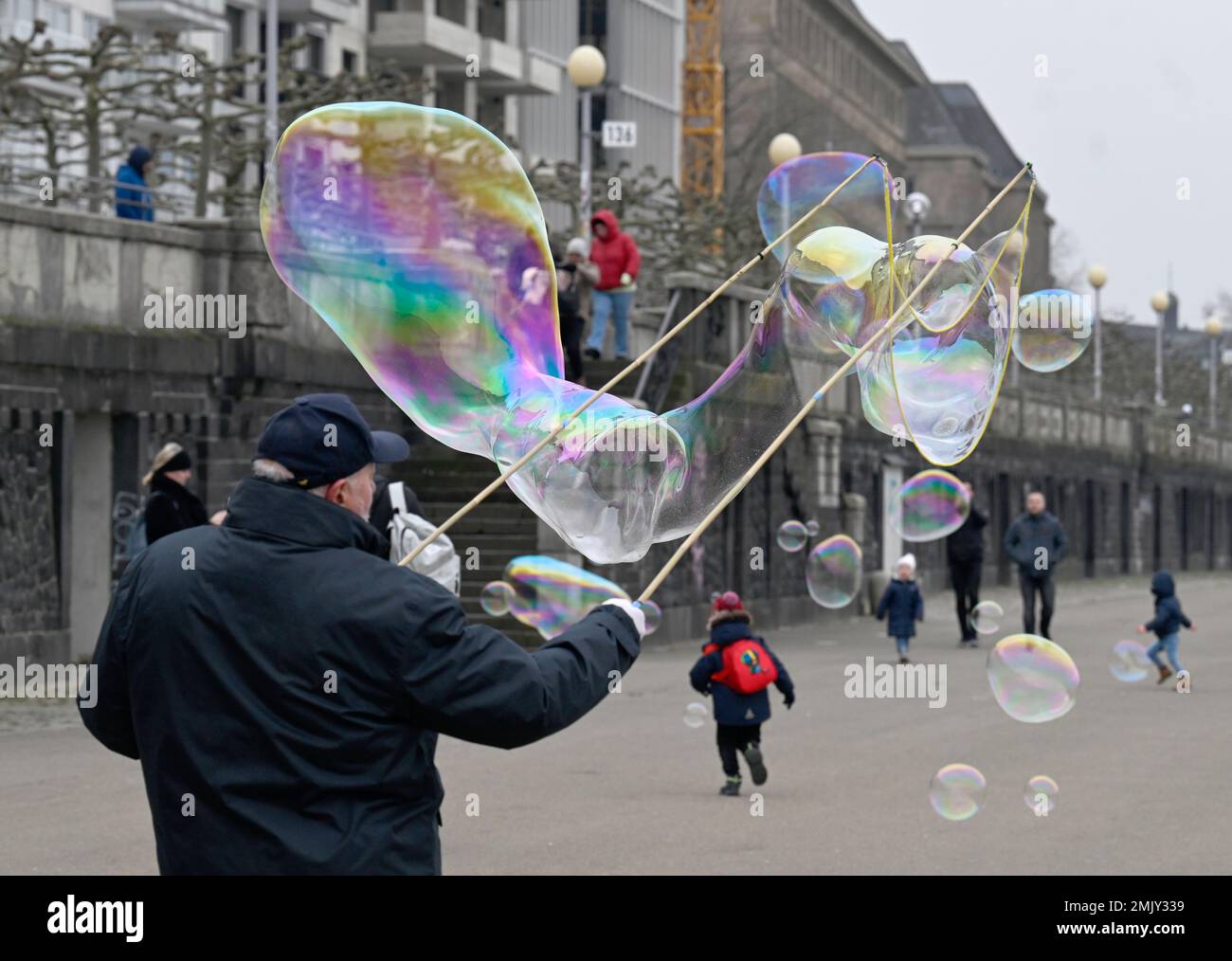 Duesseldorf, Germany. 28th Jan, 2023. A man produces giant soap bubbles on the banks of the Rhine to the delight of walkers in dreary weather with temperatures around two degrees. Credit: Roberto Pfeil/dpa/Alamy Live News Stock Photo