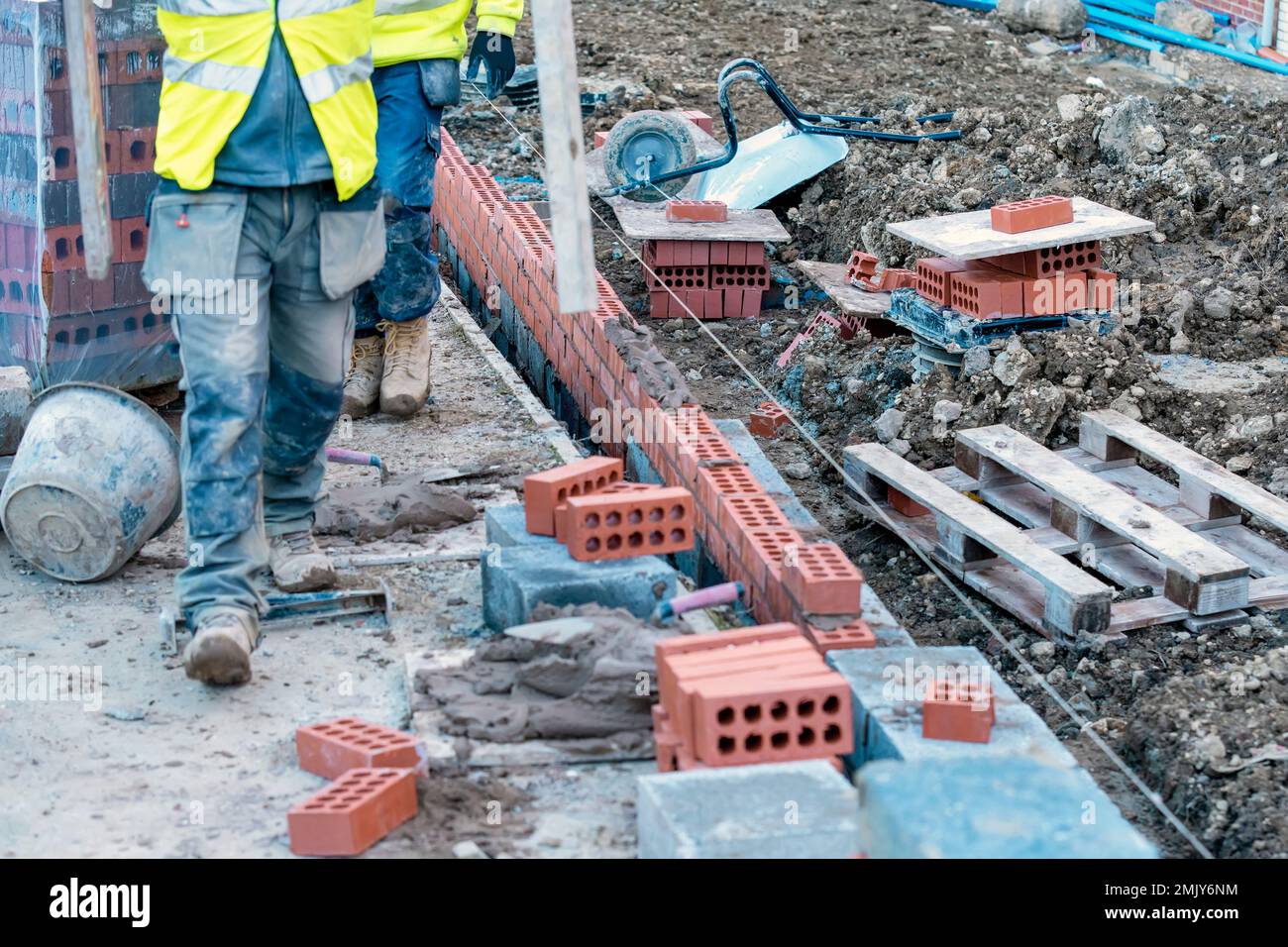 Hard working bricklayer laying concrete blocks on top of concrete