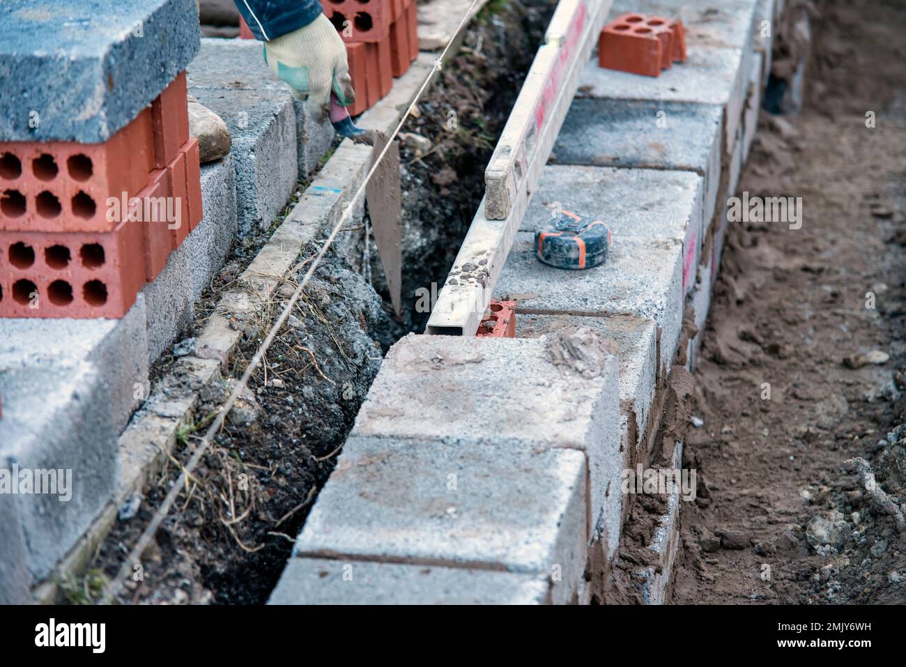 Hard working bricklayer laying concrete blocks on top of concrete