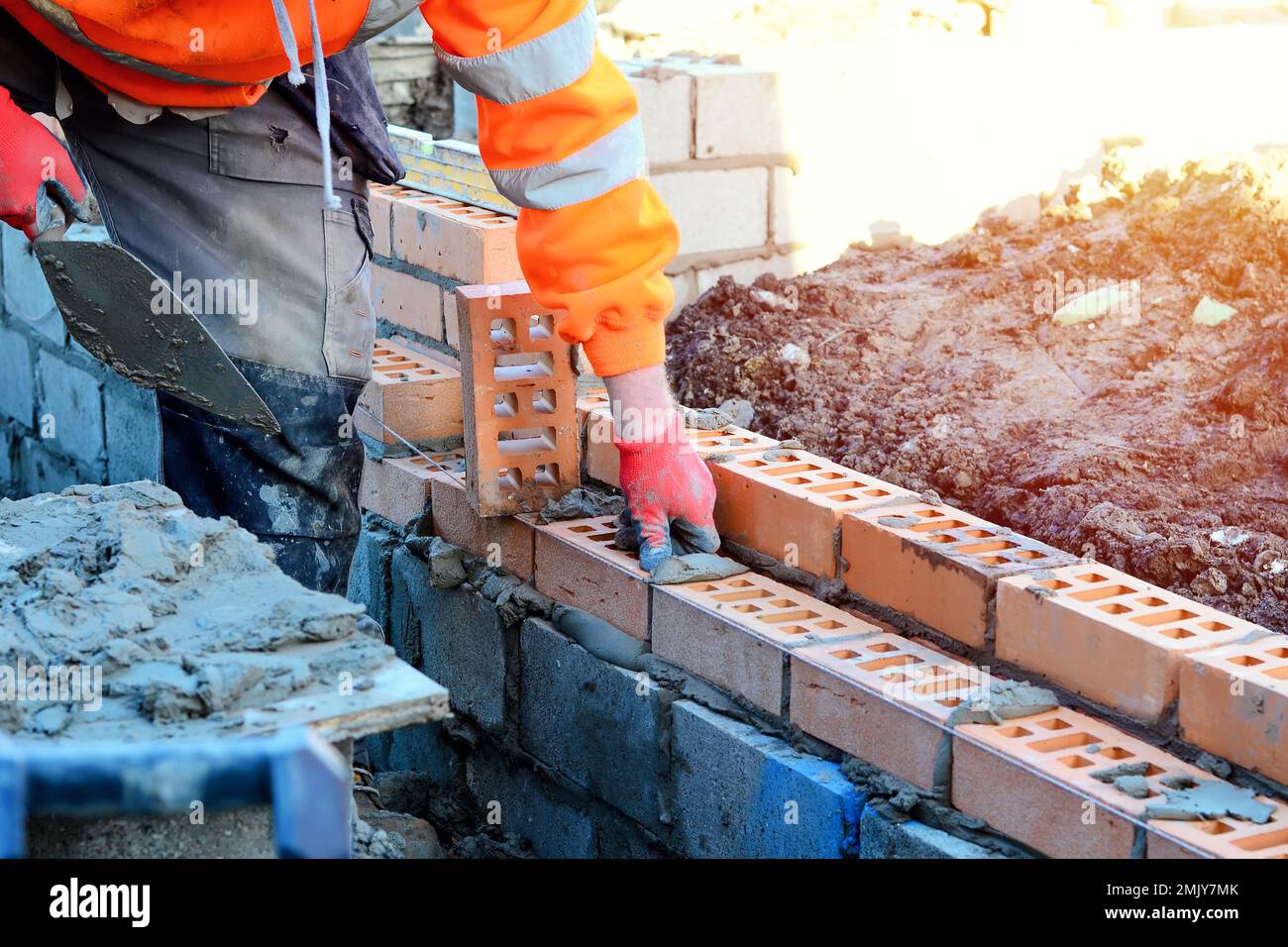 Industrial bricklayer laying bricks on cement mix on construction site