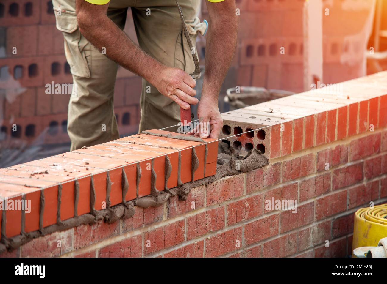Industrial bricklayer laying bricks on cement mix on construction site