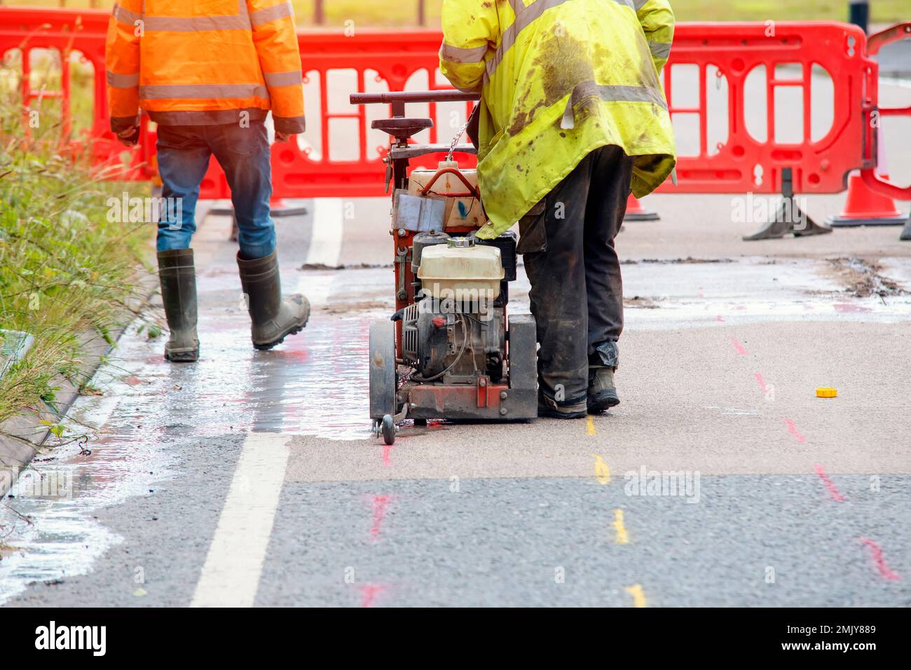 Builder using petrol powered road saw with dimond blade to cut asphalte road surface Stock Photo