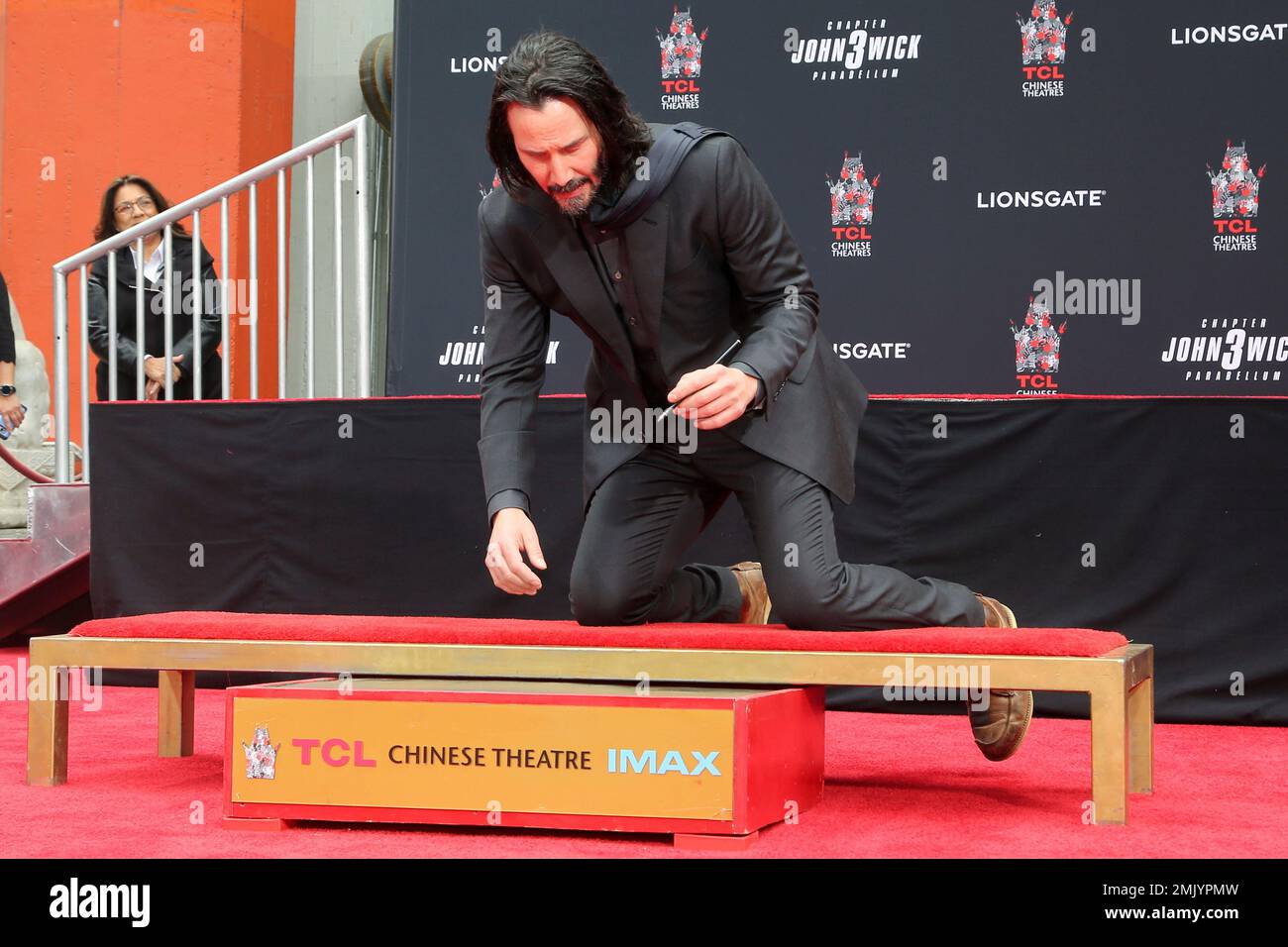 Keanu Reeves signs a cement slab during a hand and footprint ceremony ...