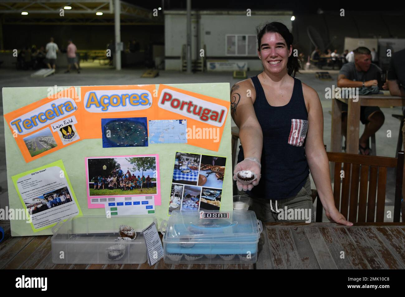 Staff Sgt. Alanna Metelka, the noncommissioned officer in charge of the 380th Air Expeditionary Wing’s legal office, holds out a Dona Amalia, a Portuguese pastry, during International Heritage Night, September 2, 2022, at Al Dhafra Air Base, United Arab Emirates. Metelka had the opportunity to visit the Azores, an island chain belonging to Portugal, while serving on Lajes Air Base. Stock Photo