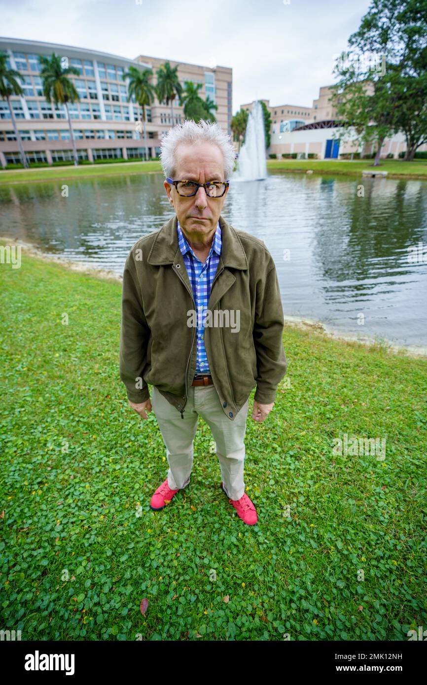 Abstract wide angle perspective of a old man college professor posing by a lake on campus Stock Photo