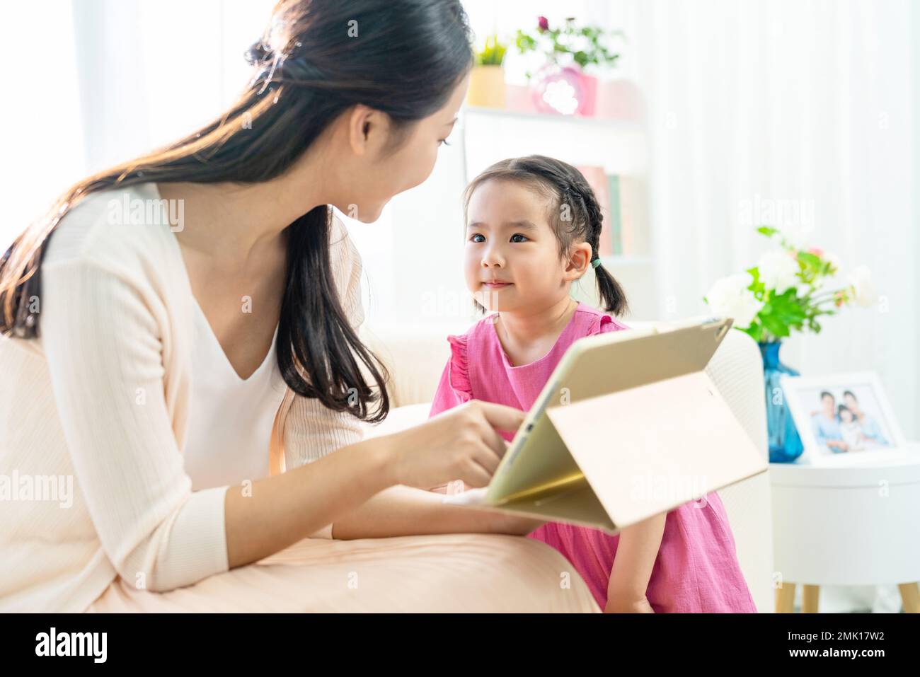 The little girl with her mother to use tablet Stock Photo