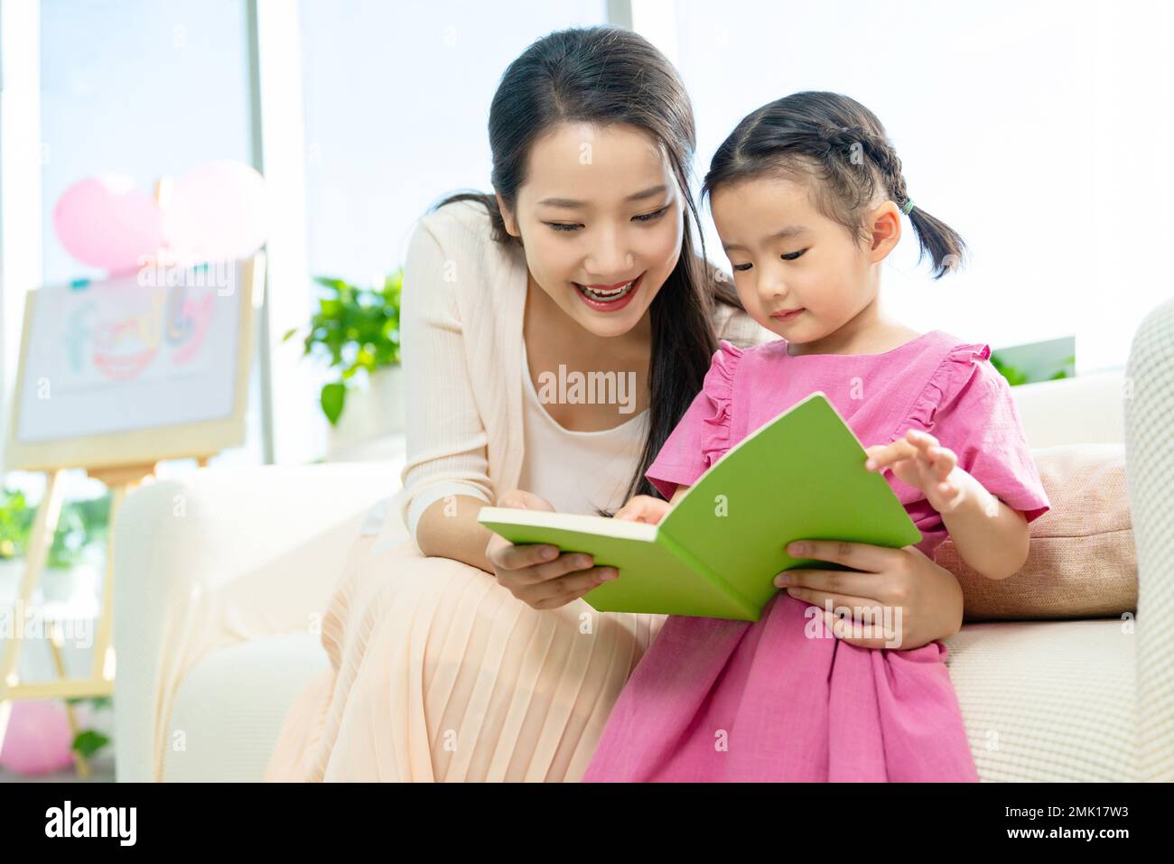 The little girl and her mother read a book together Stock Photo