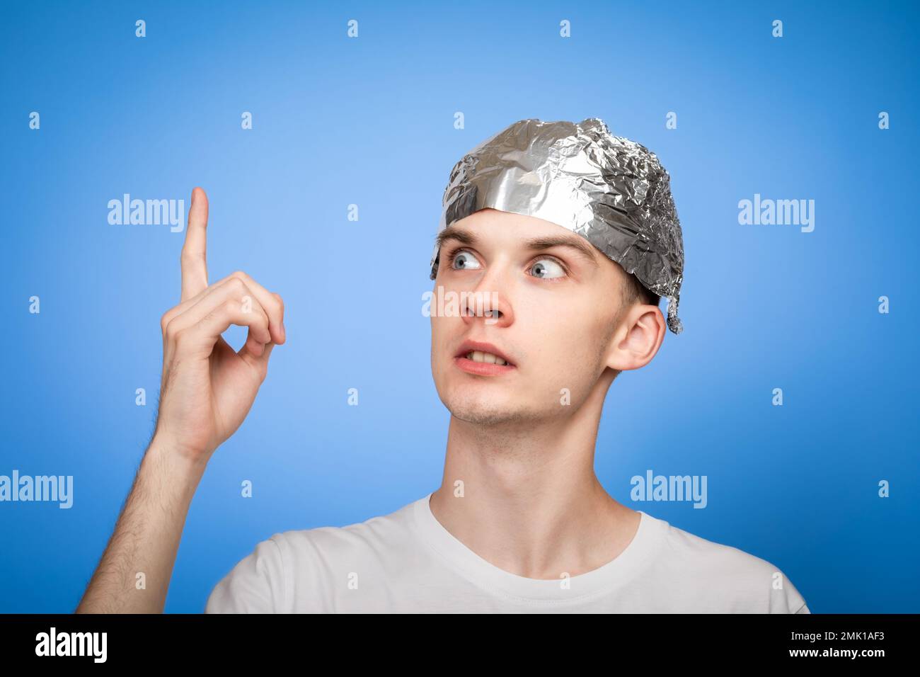 Portrait of anxious young man wearing tin foil hat pointing his finger