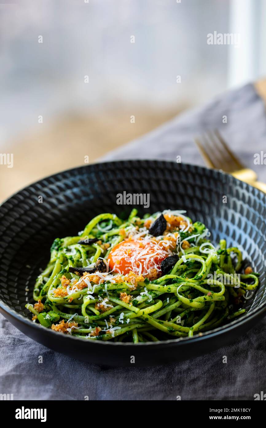 Linguine pasta with black garlic, spinach sauce and egg yolk Stock
