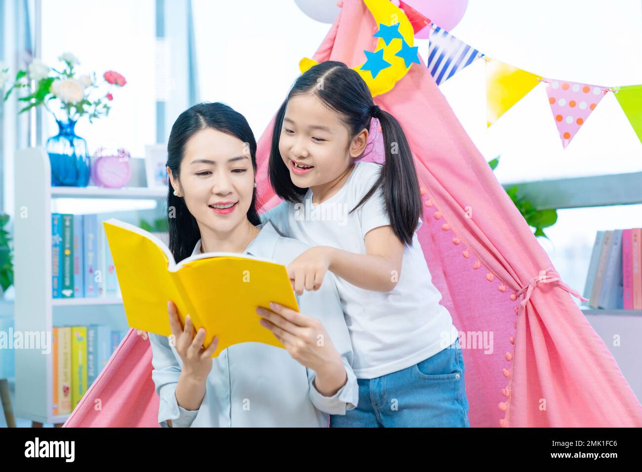 The little girl and her mother read a book together Stock Photo