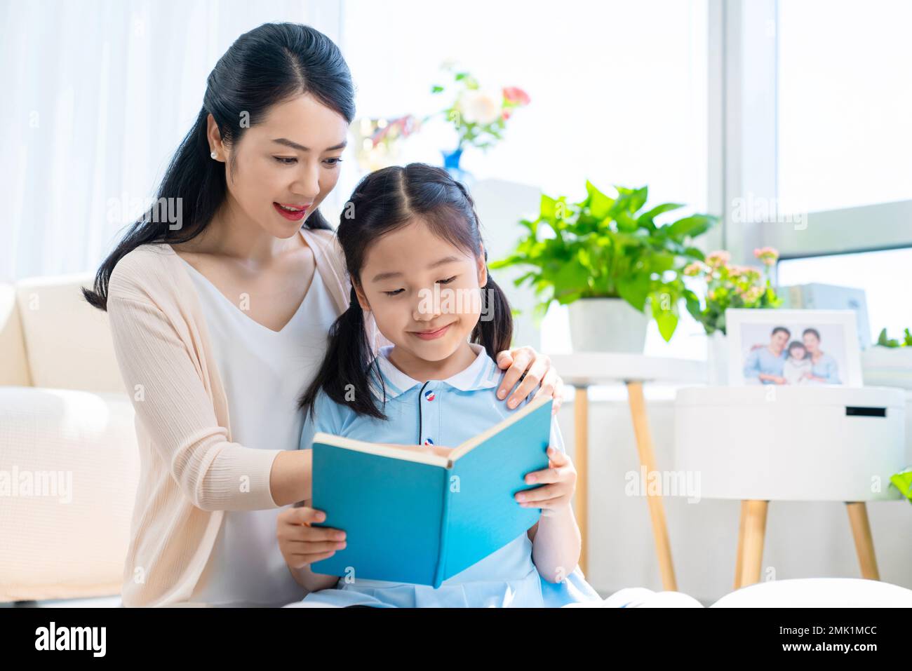 The little girl and her mother read a book together Stock Photo