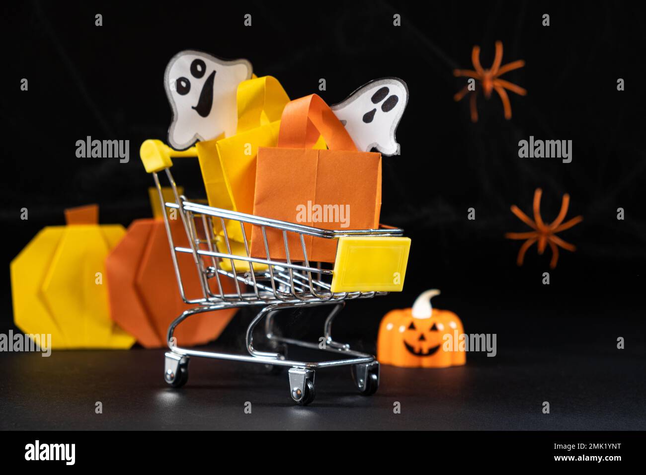 A small cart with bags, gifts on the background of pumpkins, spider webs and spiders. Halloween Sale Stock Photo