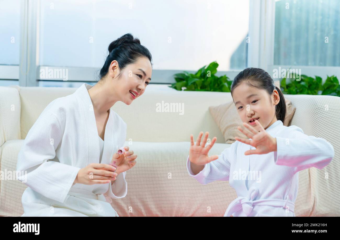 Mother to daughter wear nail polish Stock Photo