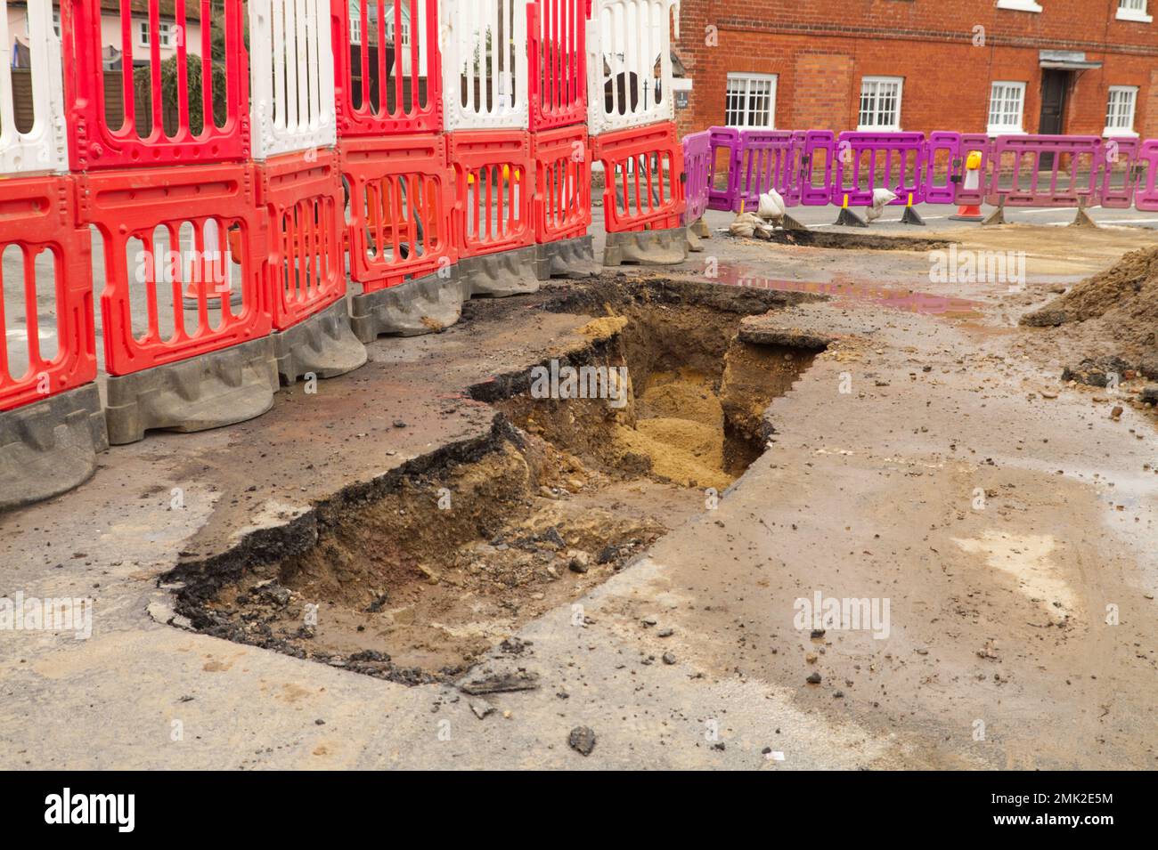 Deep trench dug out of the road near Flatford in Suffolk with barriers protecting the area. Stock Photo