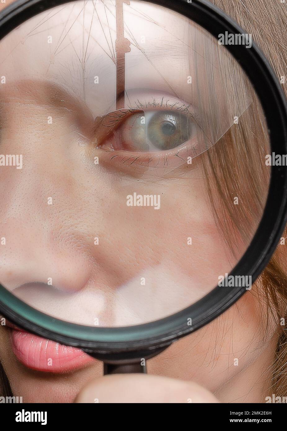 Adult woman's eye seen through magnifying glass. Reflections. Mystery Stock Photo