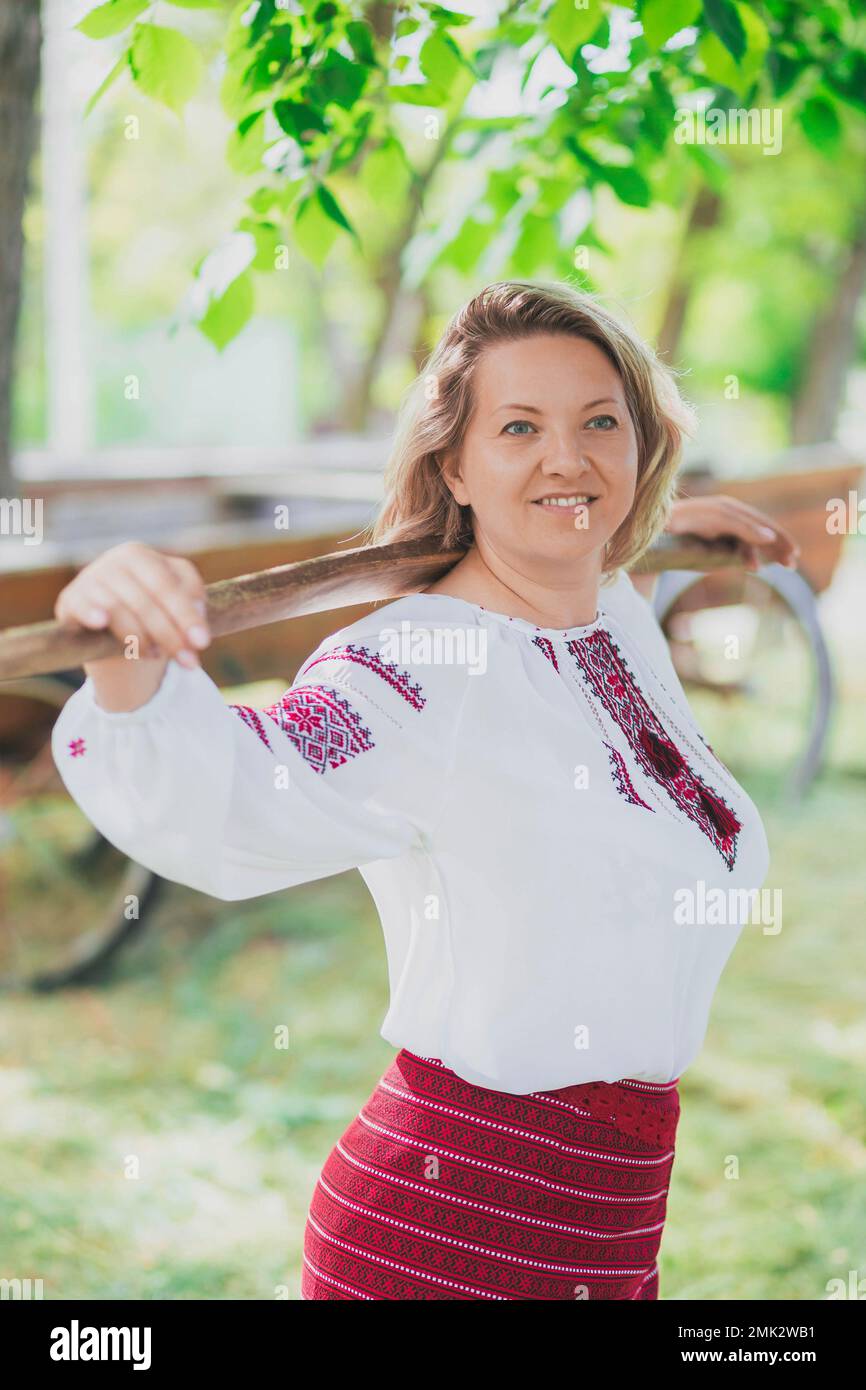 Beautiful peasant woman walks with a balance beam for buckets of water