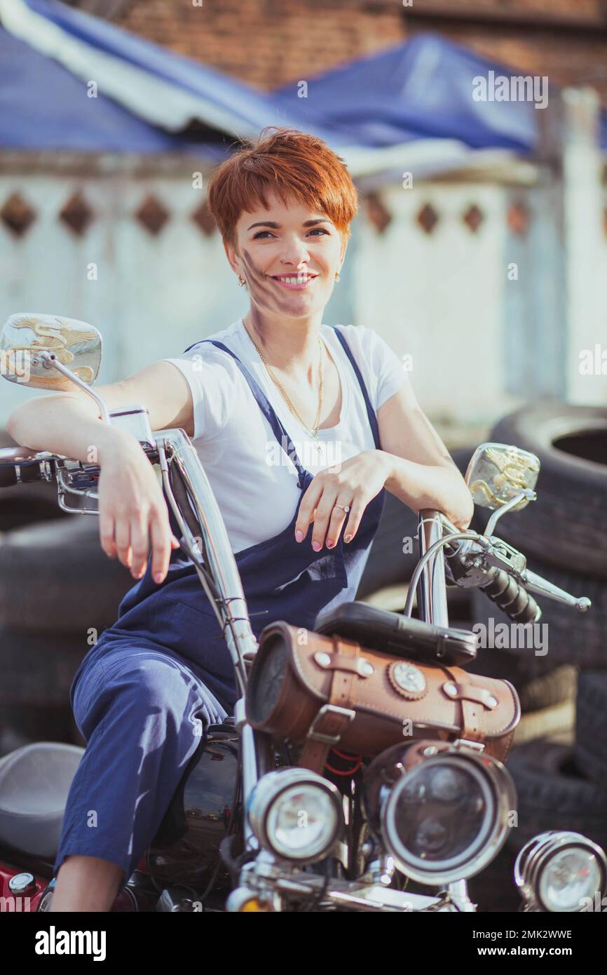 Girl auto mechanic smiling on a motorcycle Stock Photo