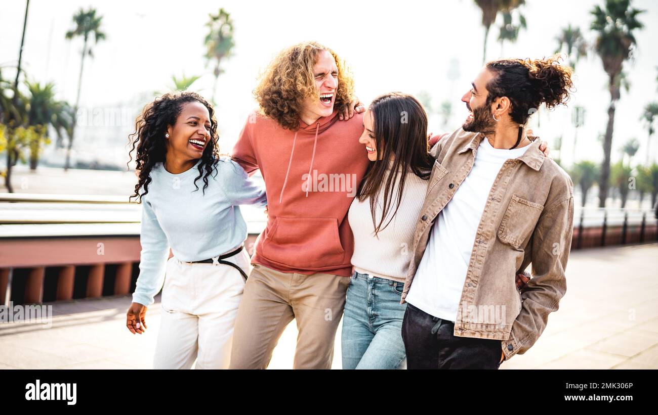 International trendy friends walking at Barceloneta waterfront boardwalk - Cool life style concept with young multiracial college students having fun Stock Photo