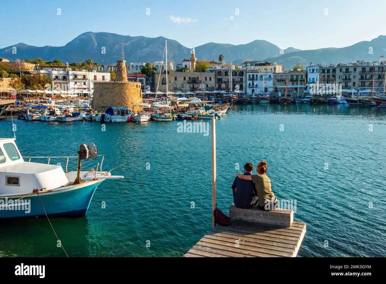 A couple sits serenely overlooking the harbor of Keryneia / Girne Stock Photo
