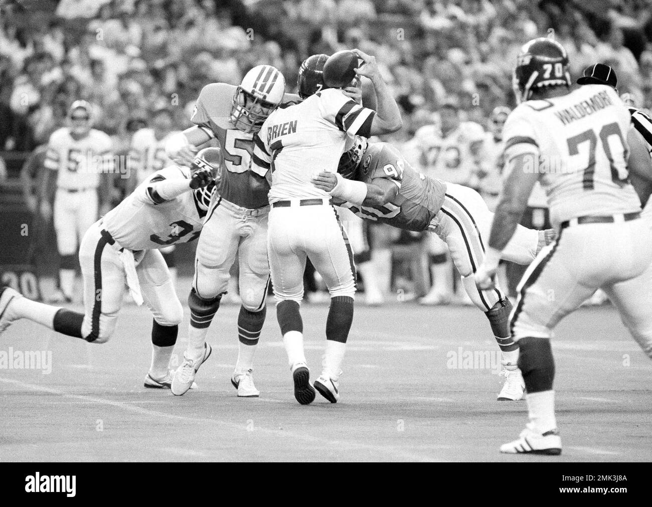 New York Jets quarterback Ken O'Brien (7) lets the football slip away as he  is sacked for a ten-yard loss by Houston Oilers Tim Joiner, left, and Bob  Hamm (90) during the