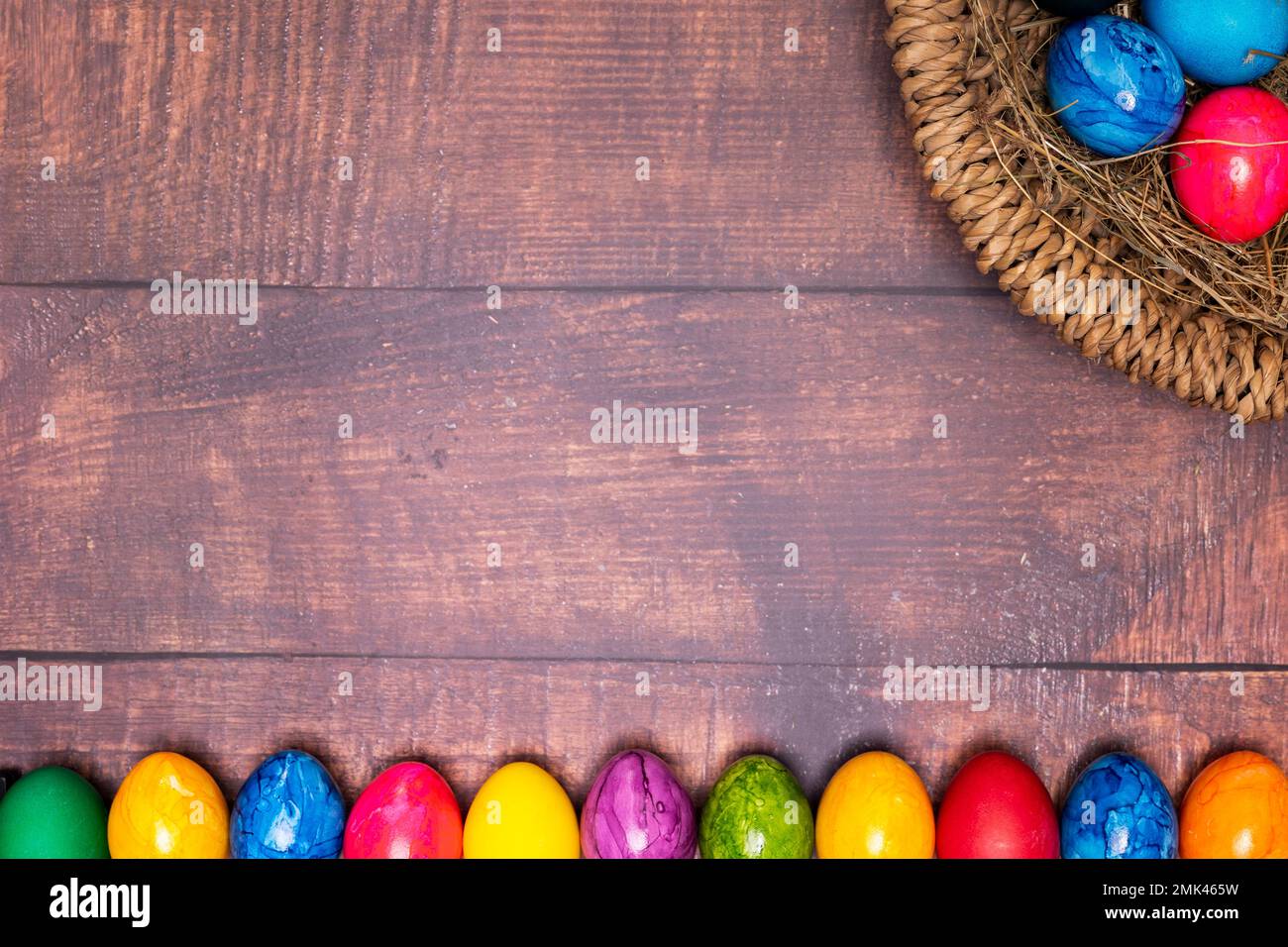 round easter basket with colorful easter eggs on rustic white wooden tabletop Stock Photo