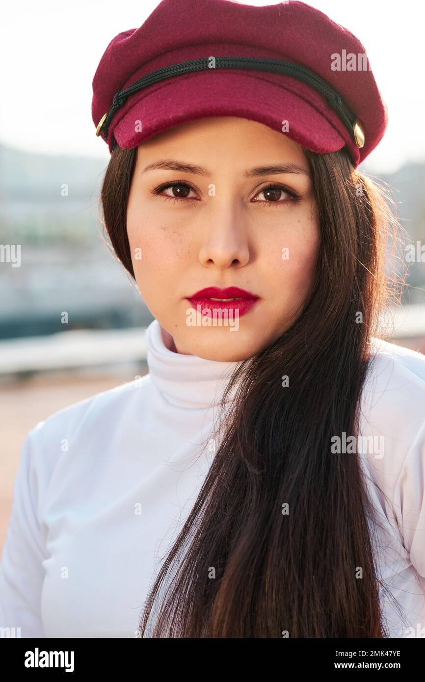 Stylish woman with beret looking at camera while posing outdoors. Stock Photo