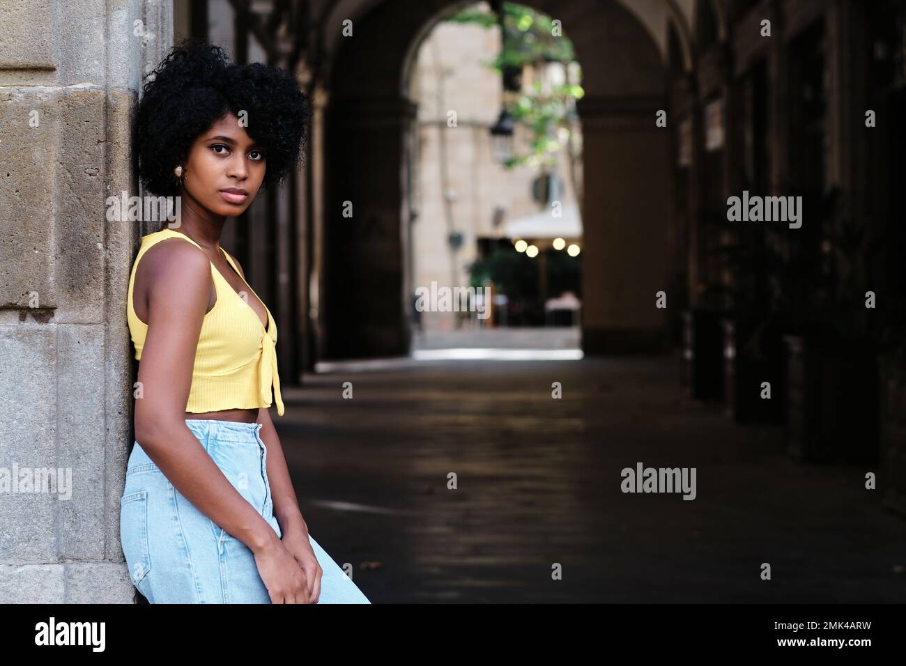 Woman with afro hair looking at camera while posing outdoors. Stock Photo