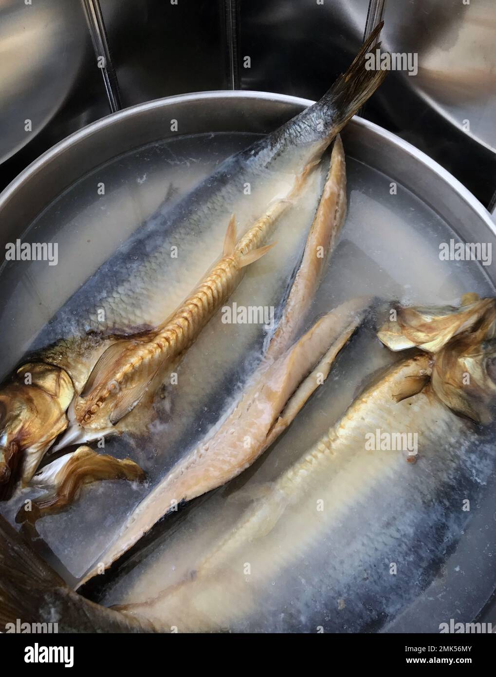 pair of kippers poaching in a stainless steel  frying pan Stock Photo