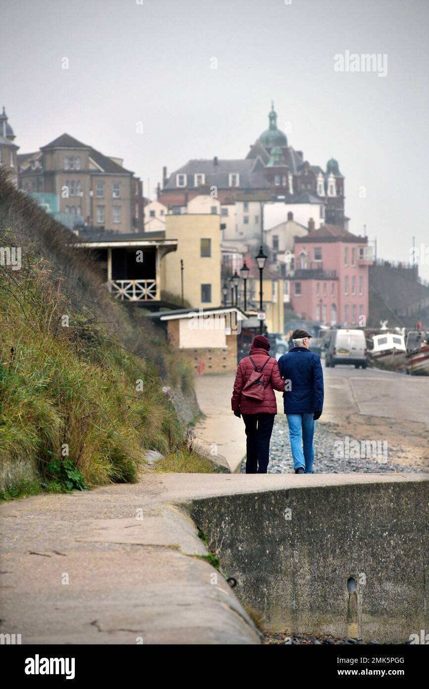 middle aged couple walking along sea front at cromer norfolk england arm in arm Stock Photo