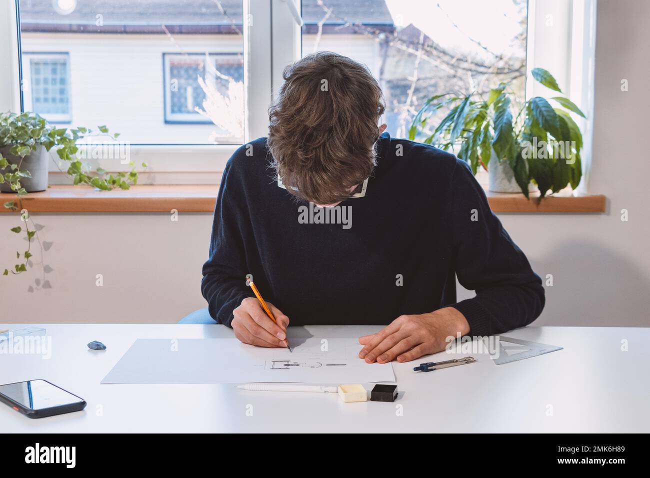 Brown-haired young architect creates new product designs for a new ...