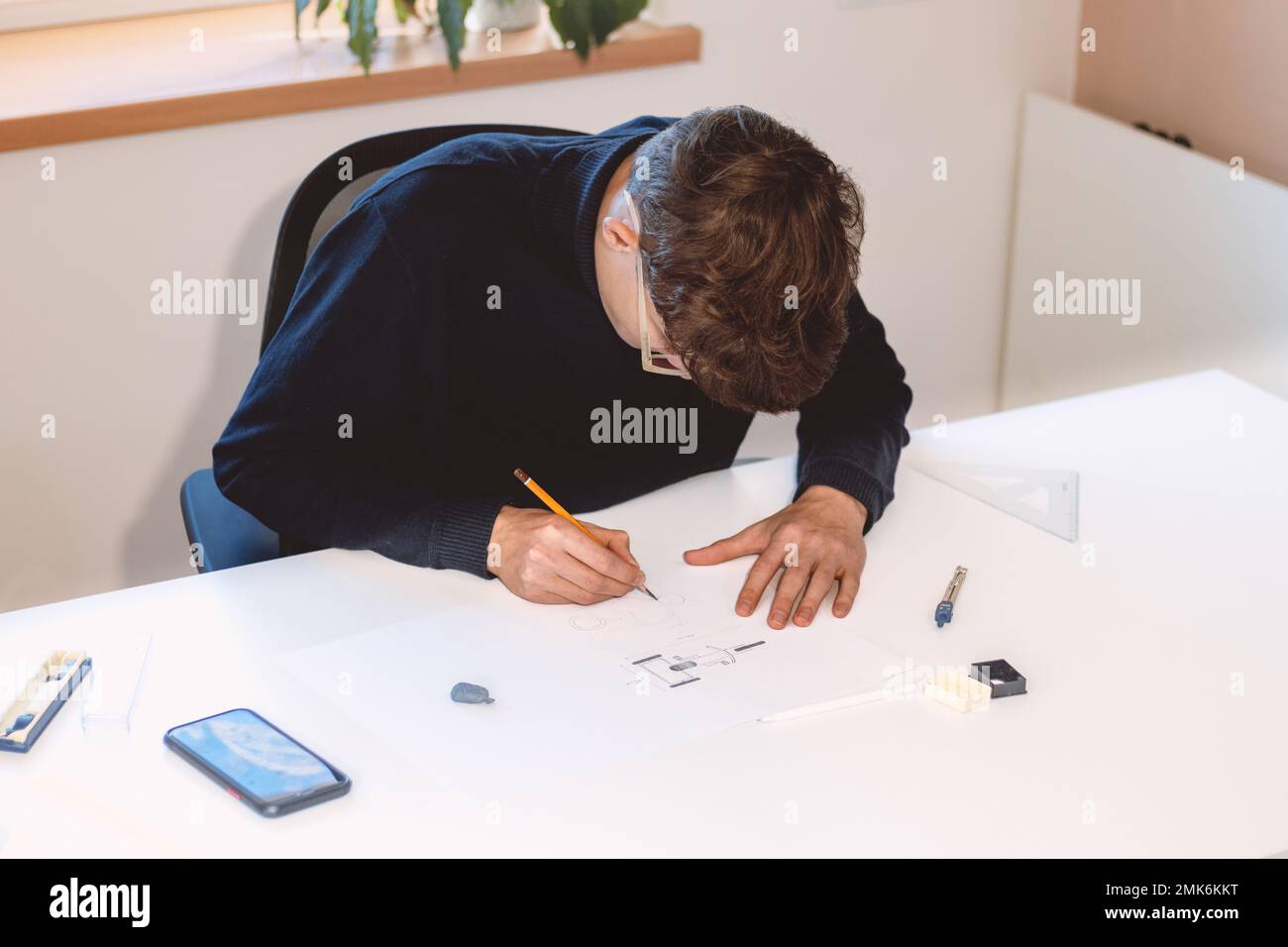 Brown-haired young architect creates new product designs for a new ...