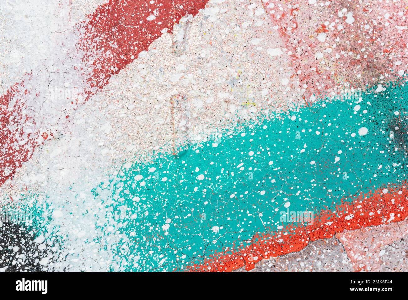 Macro close-up of a wall spray painted with white, red and turquoise. Colorful splashes and splatter. Abstract textured splattered graffiti background. Stock Photo