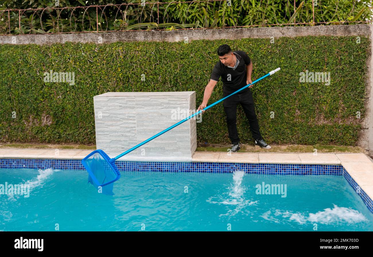 Swimming pool cleaning and maintenance concept. Maintenance person cleaning a swimming pool with