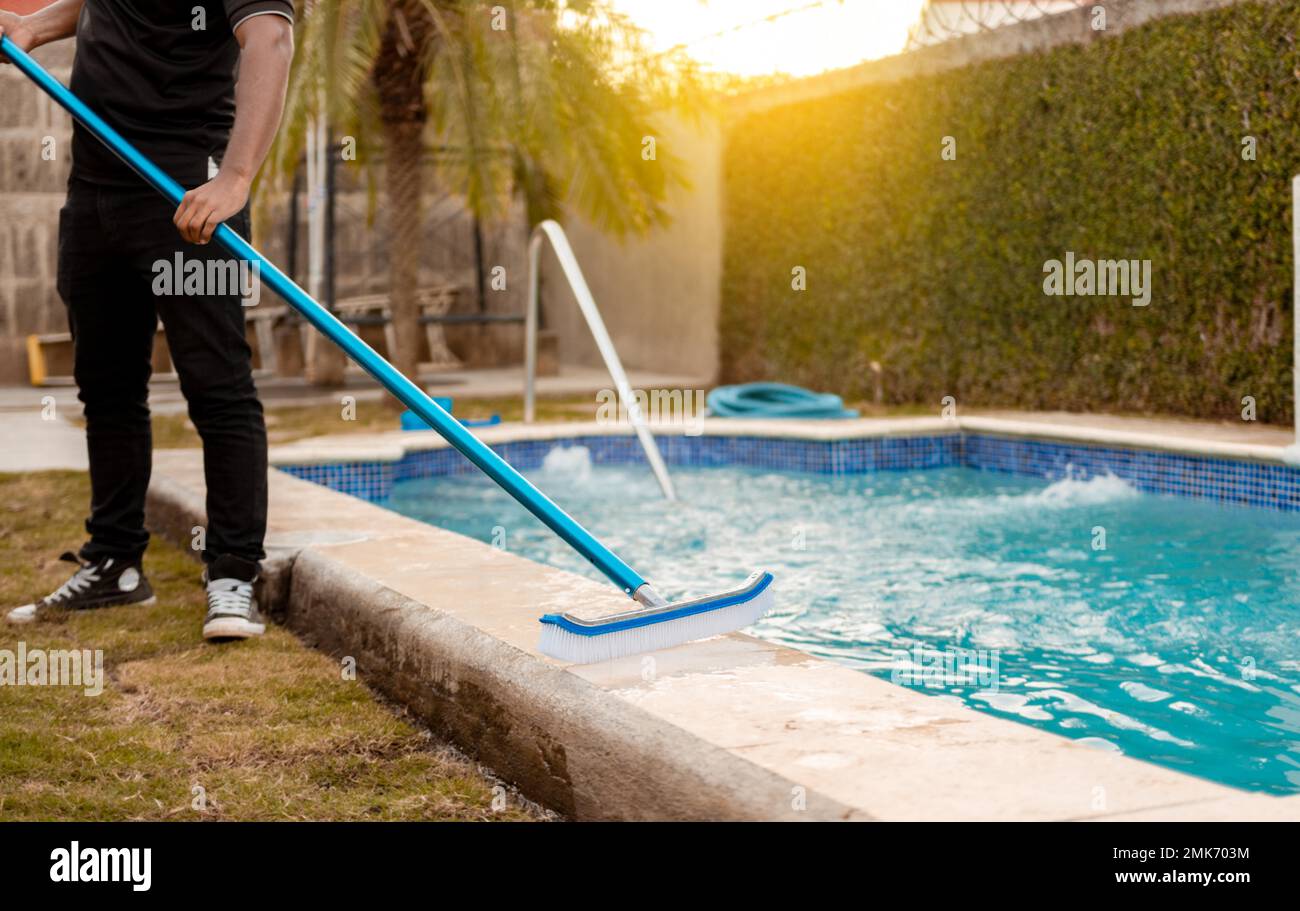 Hands of worker cleaning a swimming pool with special brush, Maintenance person cleaning