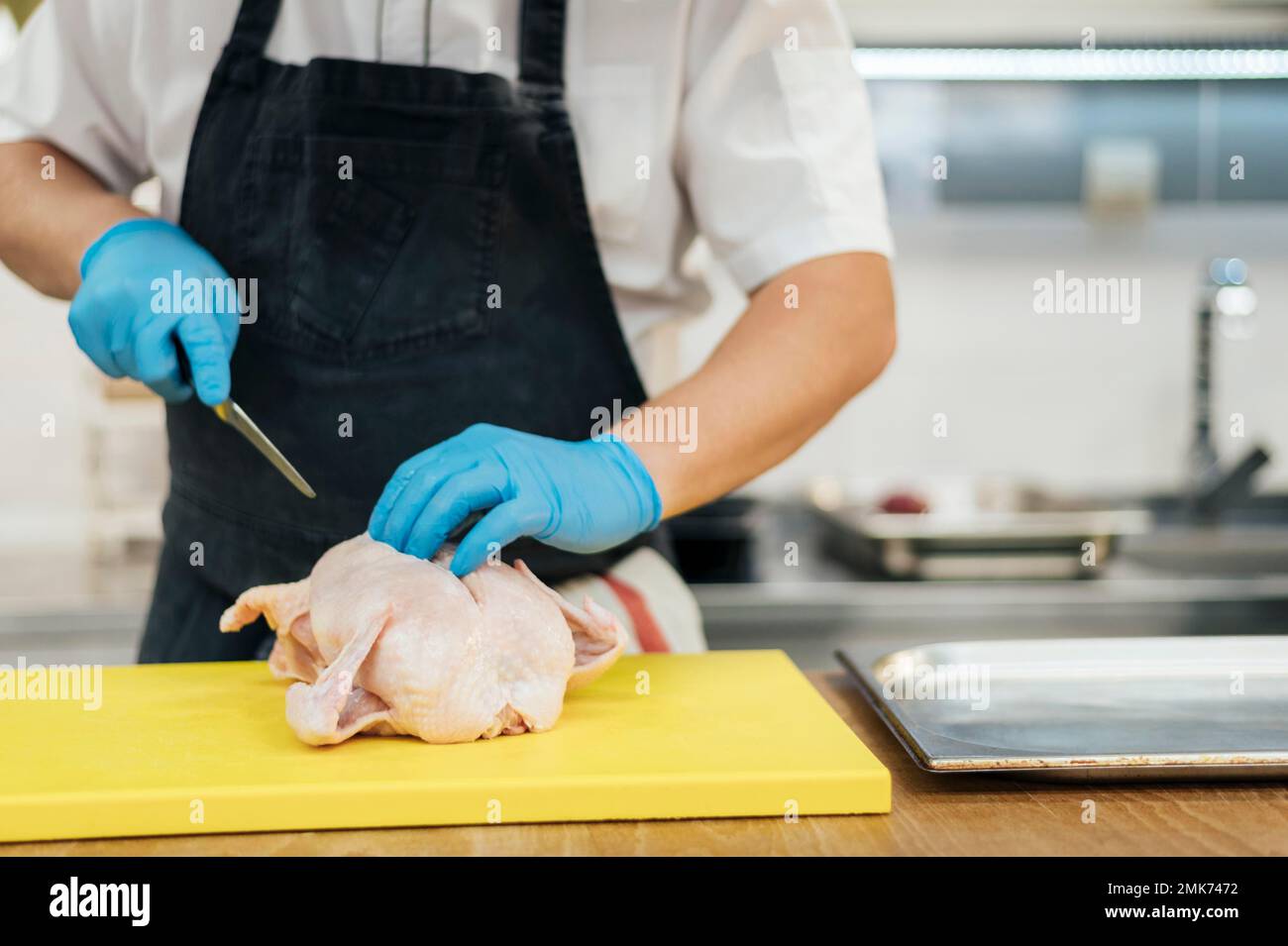 front view chef with gloves cutting chicken. High resolution photo