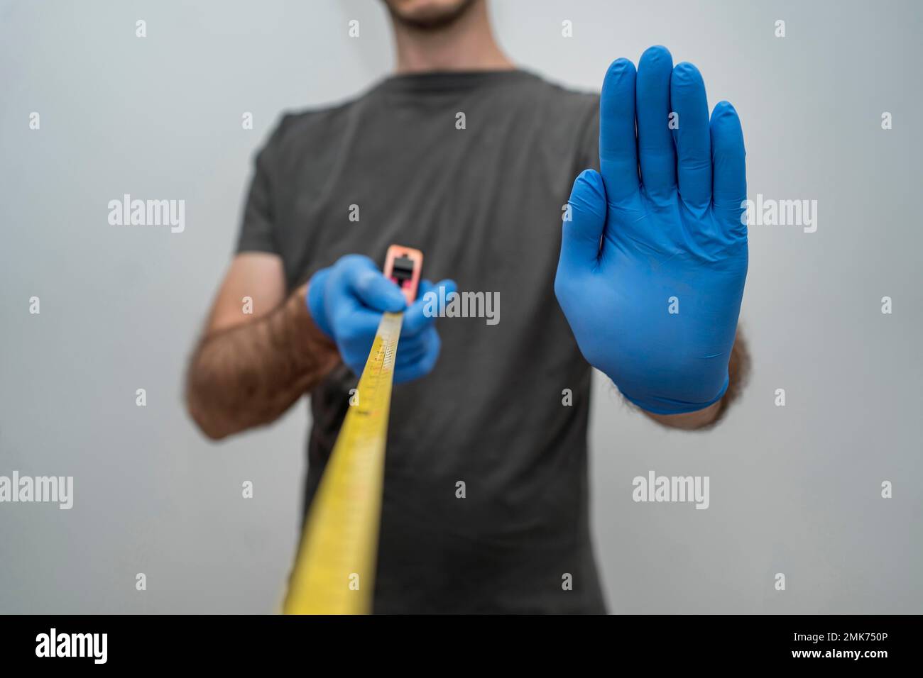 man with gloves holding tape measurer social distancing. High resolution photo Stock Photo