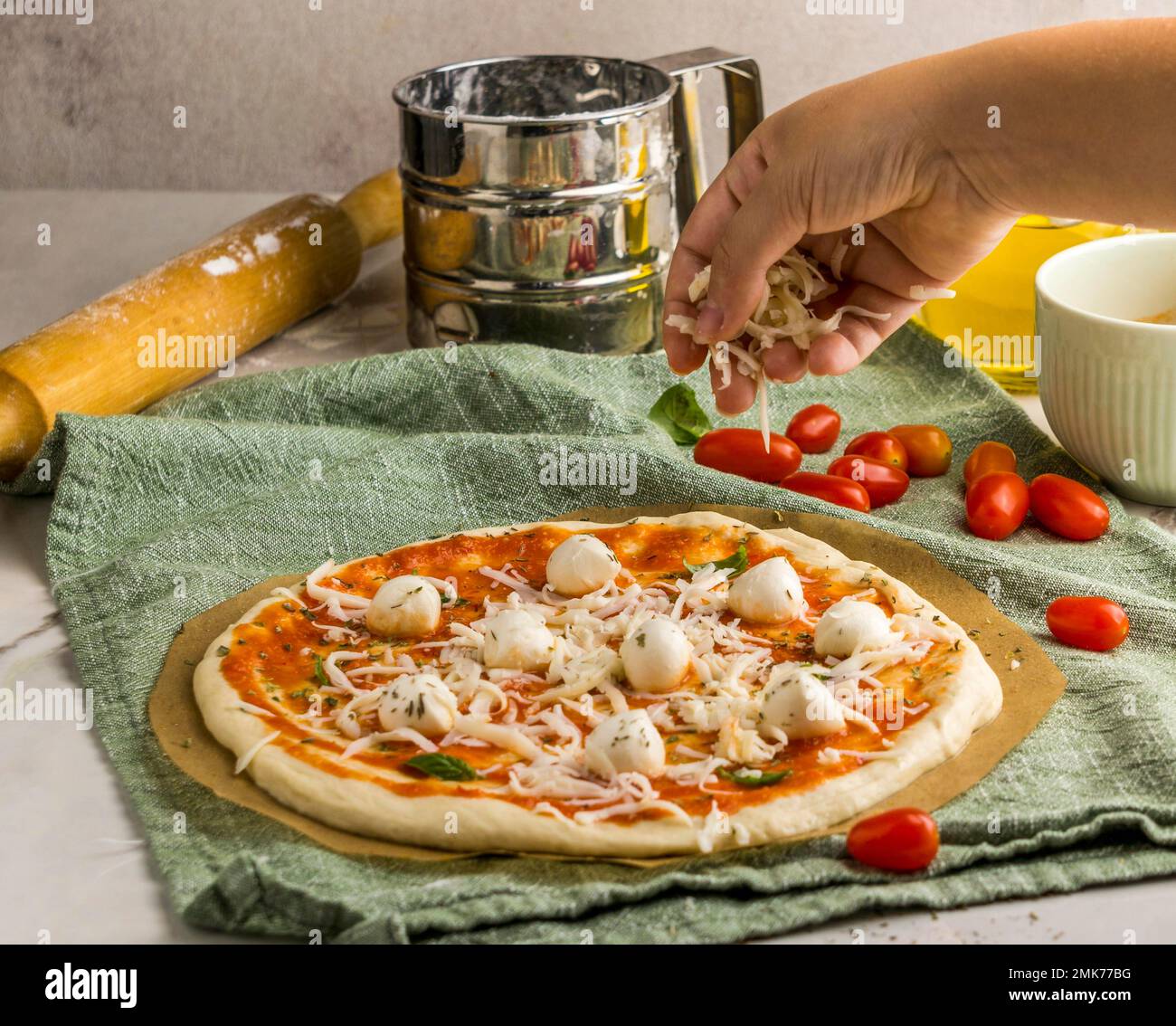 person sprinkling mozzarella cheese pizza. High resolution photo Stock