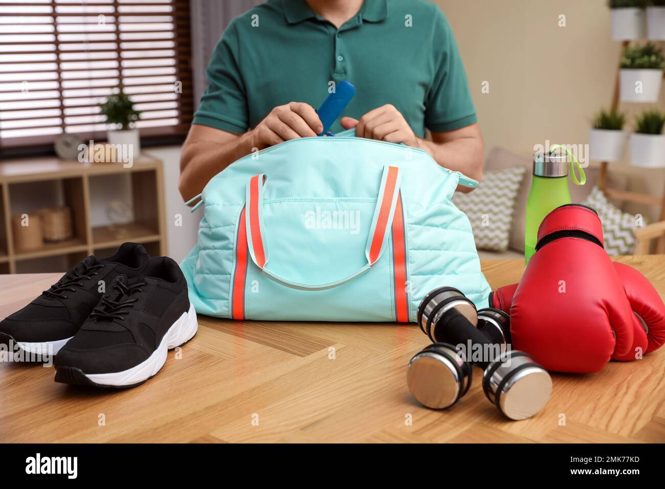 Man packing sports bag for training indoors, closeup Stock Photo