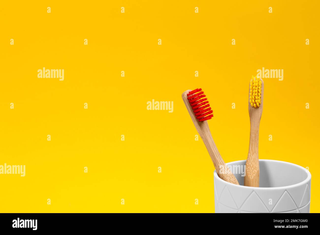 Toothbrushes made of bamboo in holder on yellow background. Space for ...