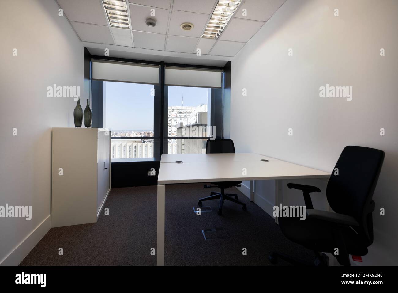 Small office with facing office desks with black swivel chairs in an